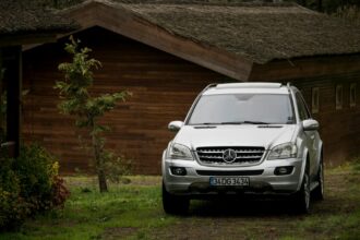 A sleek Mercedes-Benz SUV parked near a rustic wooden house in Istanbul, captured during the day.